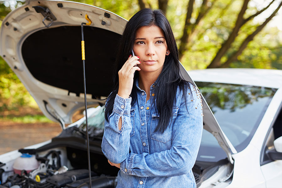 Woman on phone next to broken down car